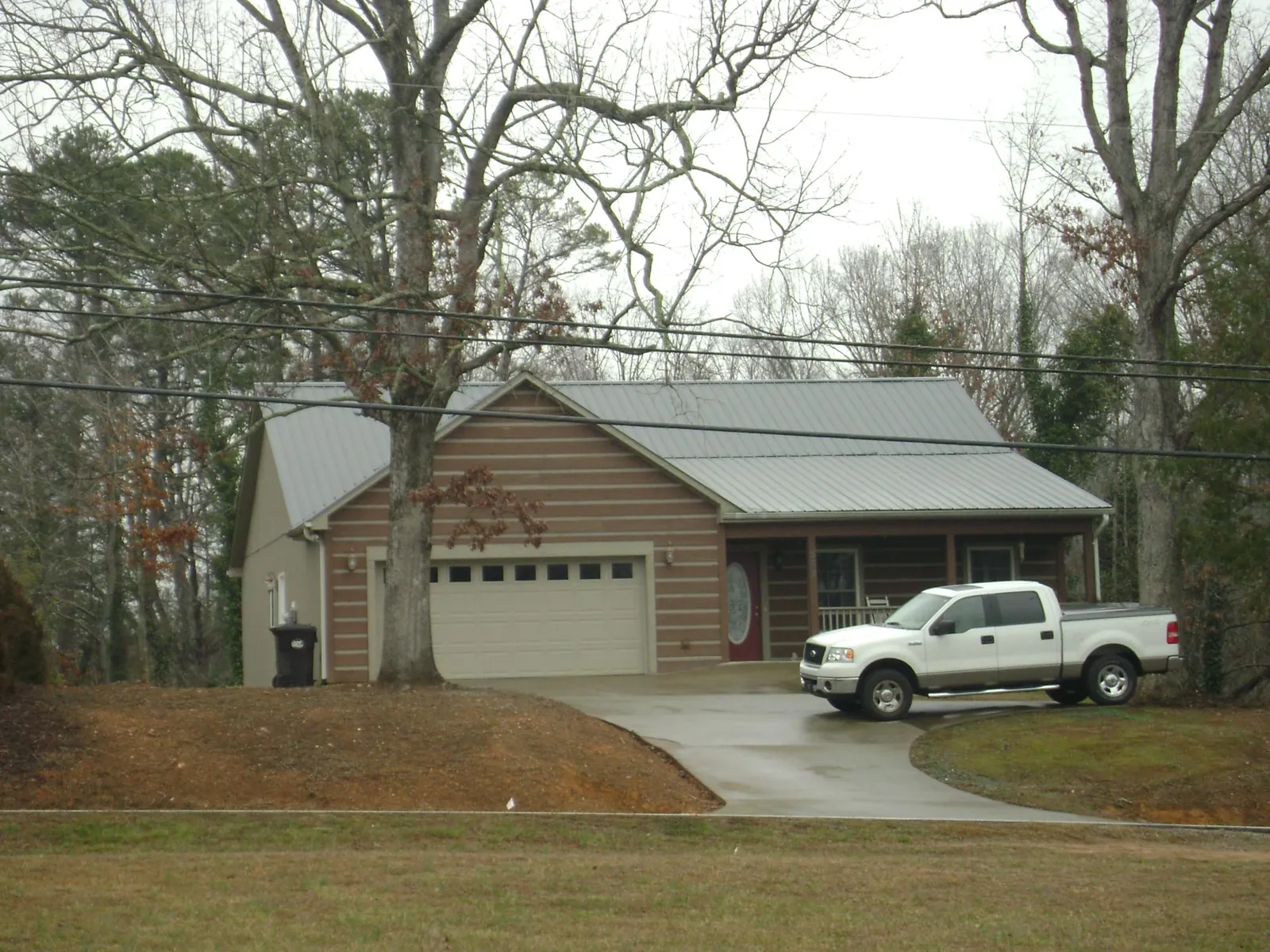 Gray metal roof on a log sided house with an attached two car garage in Madisonville